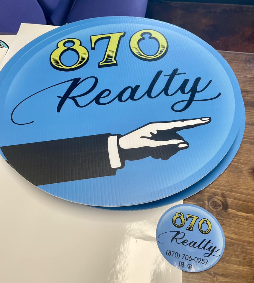 Blue oval corrugated plastic yard sign and button for 870 Realty with pointing hand graphic.