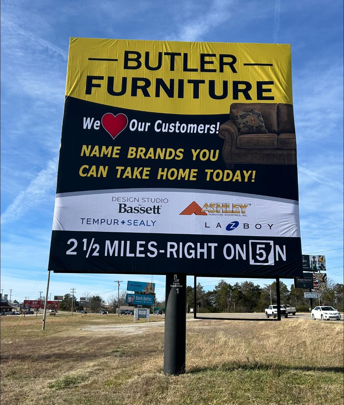 Large yellow and black pylon sign for Butler Furniture with navigation directions.