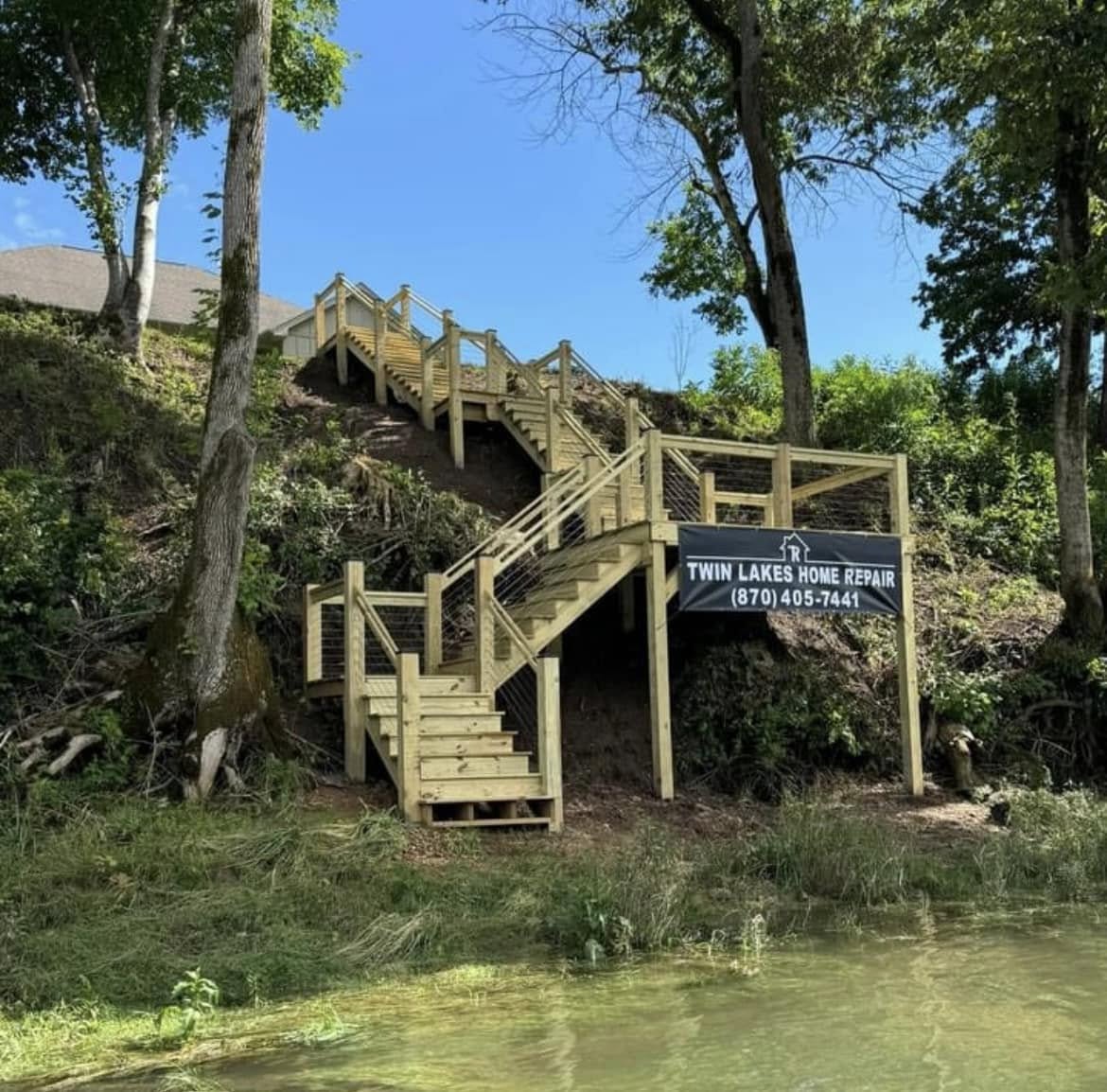 Black vinyl banner for Twin Lakes Home Repair on string railing of outdoor wooden stairs