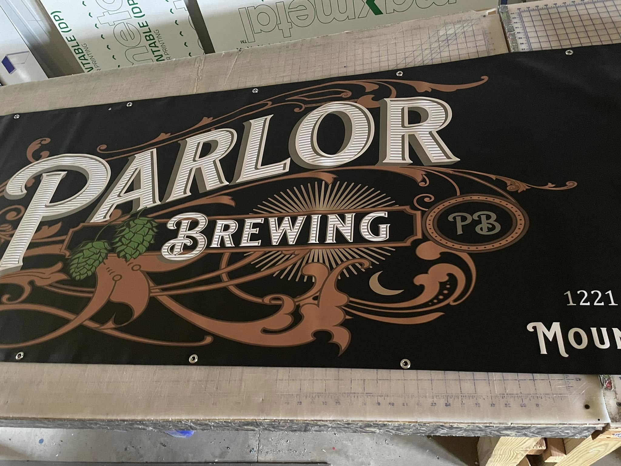 Custom-printed black vinyl banner with cream and brown typography for Parlor Brewing, complete with grommets.