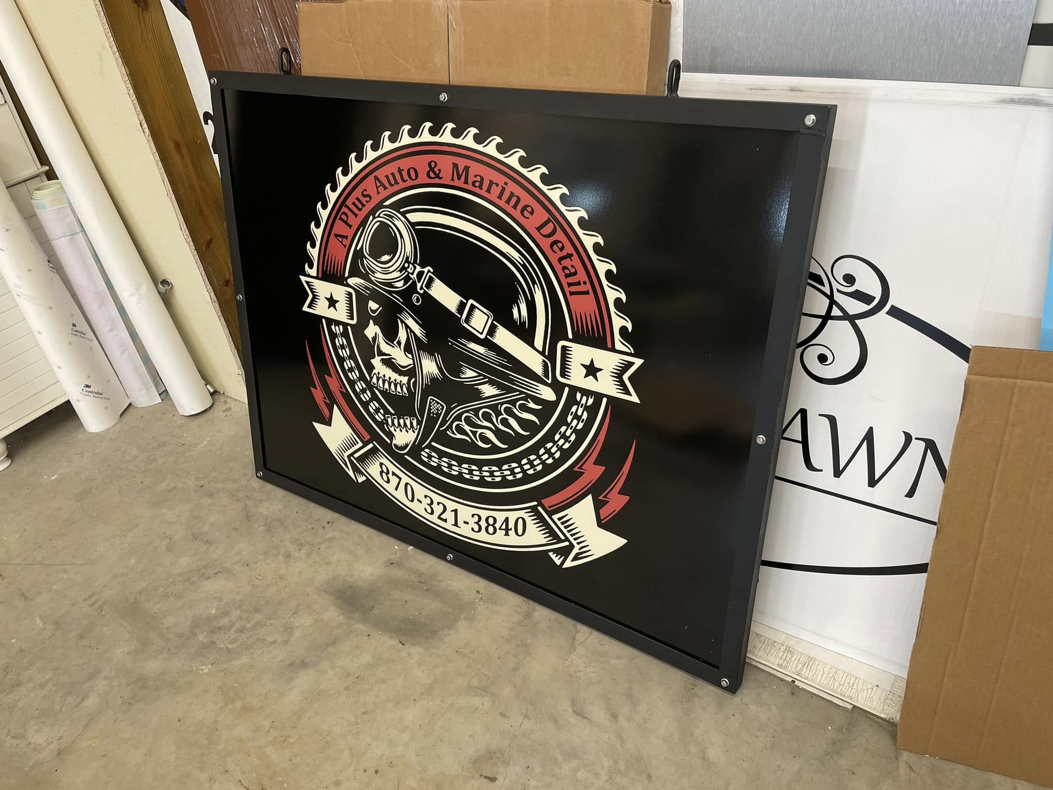 Black rectangular storefront sign for A Plus Auto & Marine Detail with logo and phone number.
