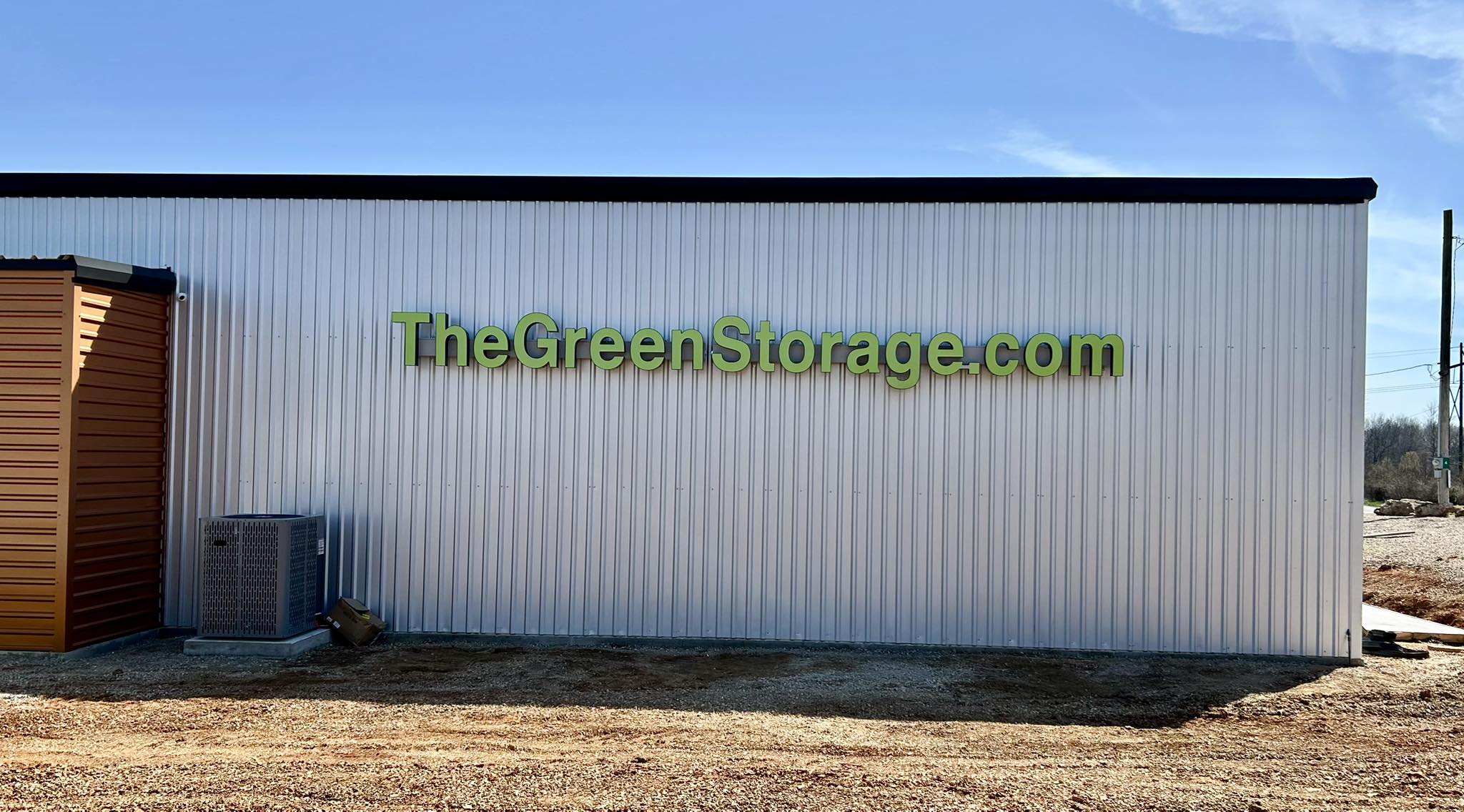 Green dimensional letters for TheGreenStorage.com website mounted on a corrugated metal building.