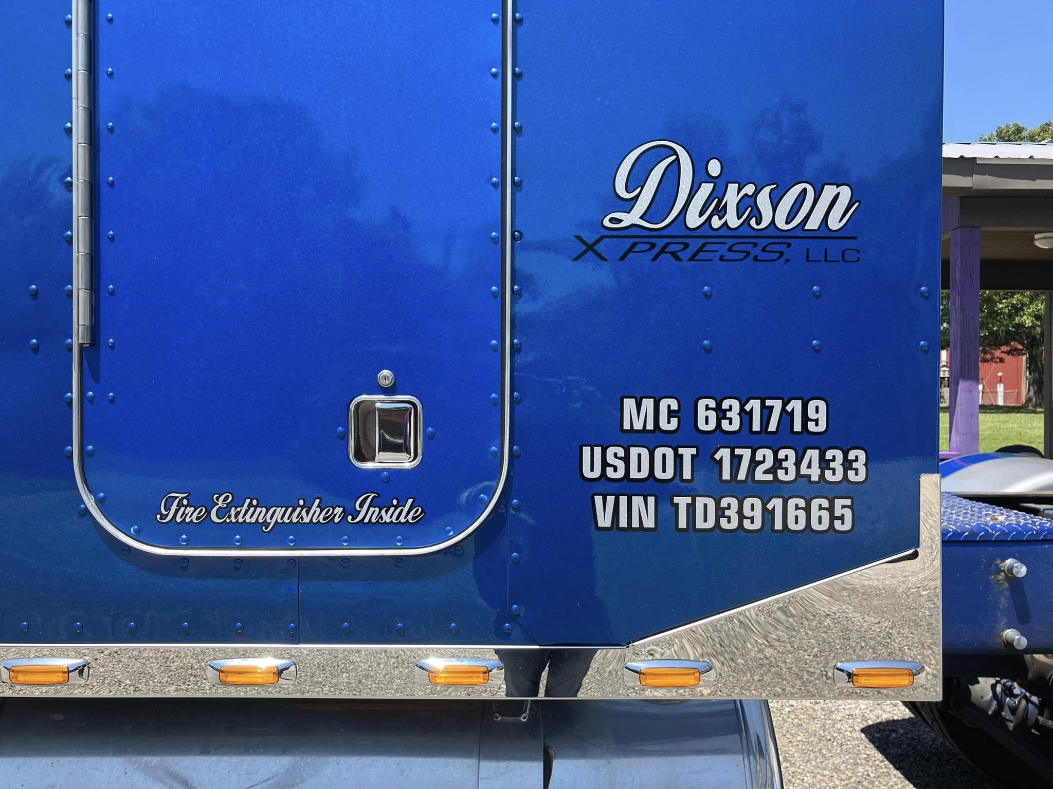 Custom vinyl graphics on a blue semi-truck for Dixon Xpress, including DOT and VIN numbers.