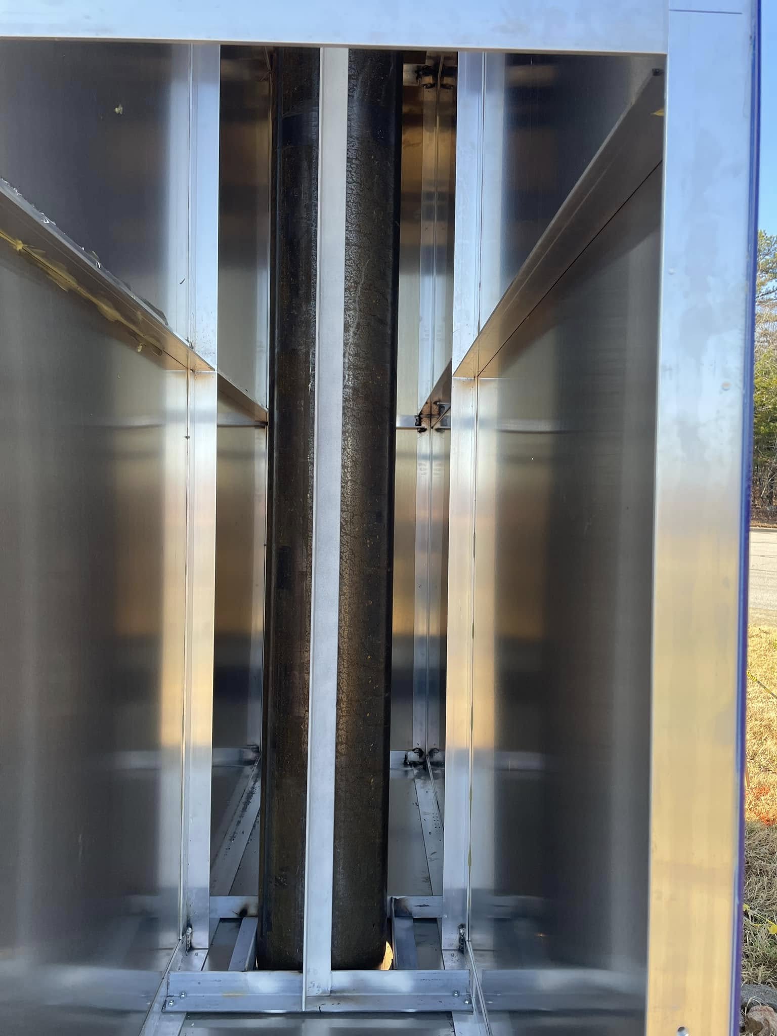 Stainless steel access panel on a pole sign structure with internal tubing and wiring.