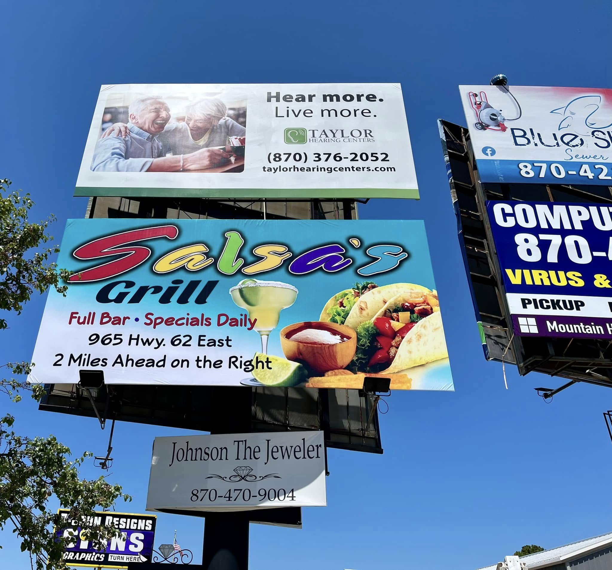 Outdoor billboard signs for Taylor Hearing Centers, Salsa's Grill, Blue S Plumbing, Computer Repair, and Johnson The Jeweler