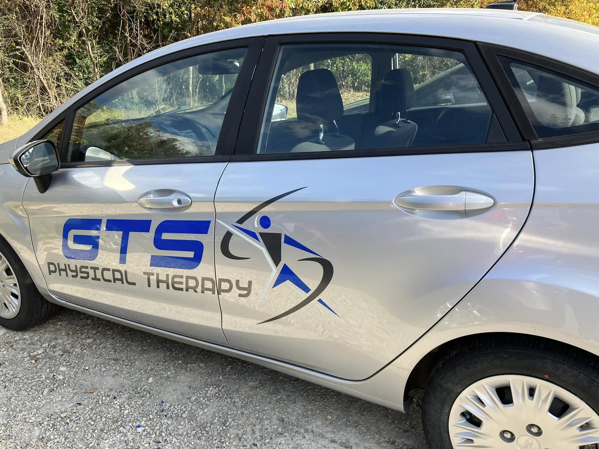 Custom vinyl graphics for GTS Physical Therapy on a silver sedan, featuring company logo and name.