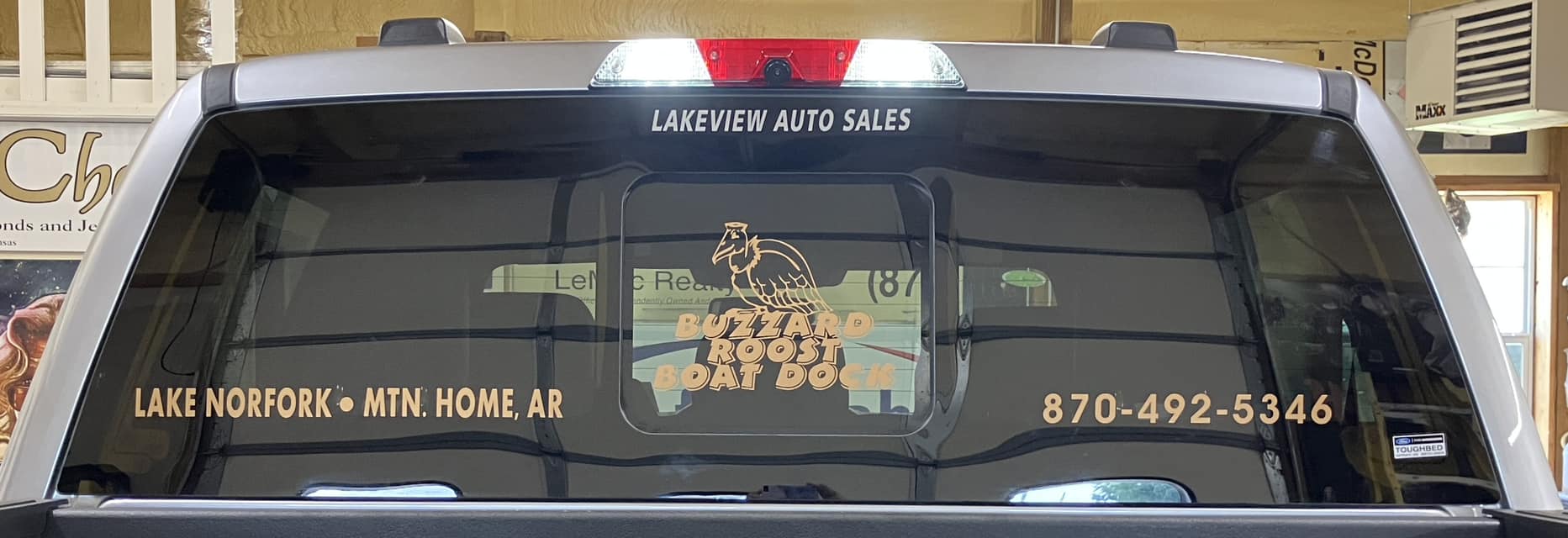 Custom gold vinyl graphics for Buzzard Roost Boat Dock on the back window of a truck.