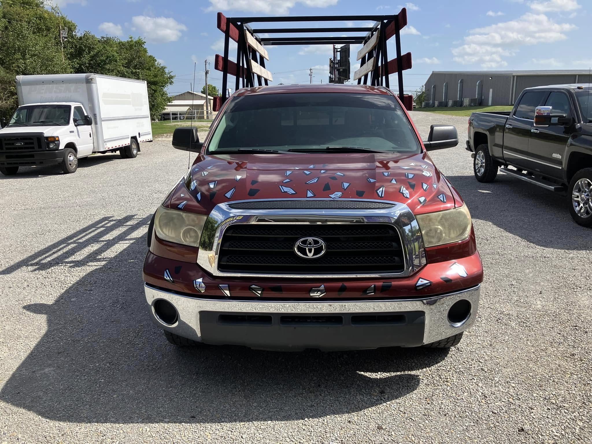 Red Toyota Tundra with partial geometric vinyl wrap on the hood and fender.