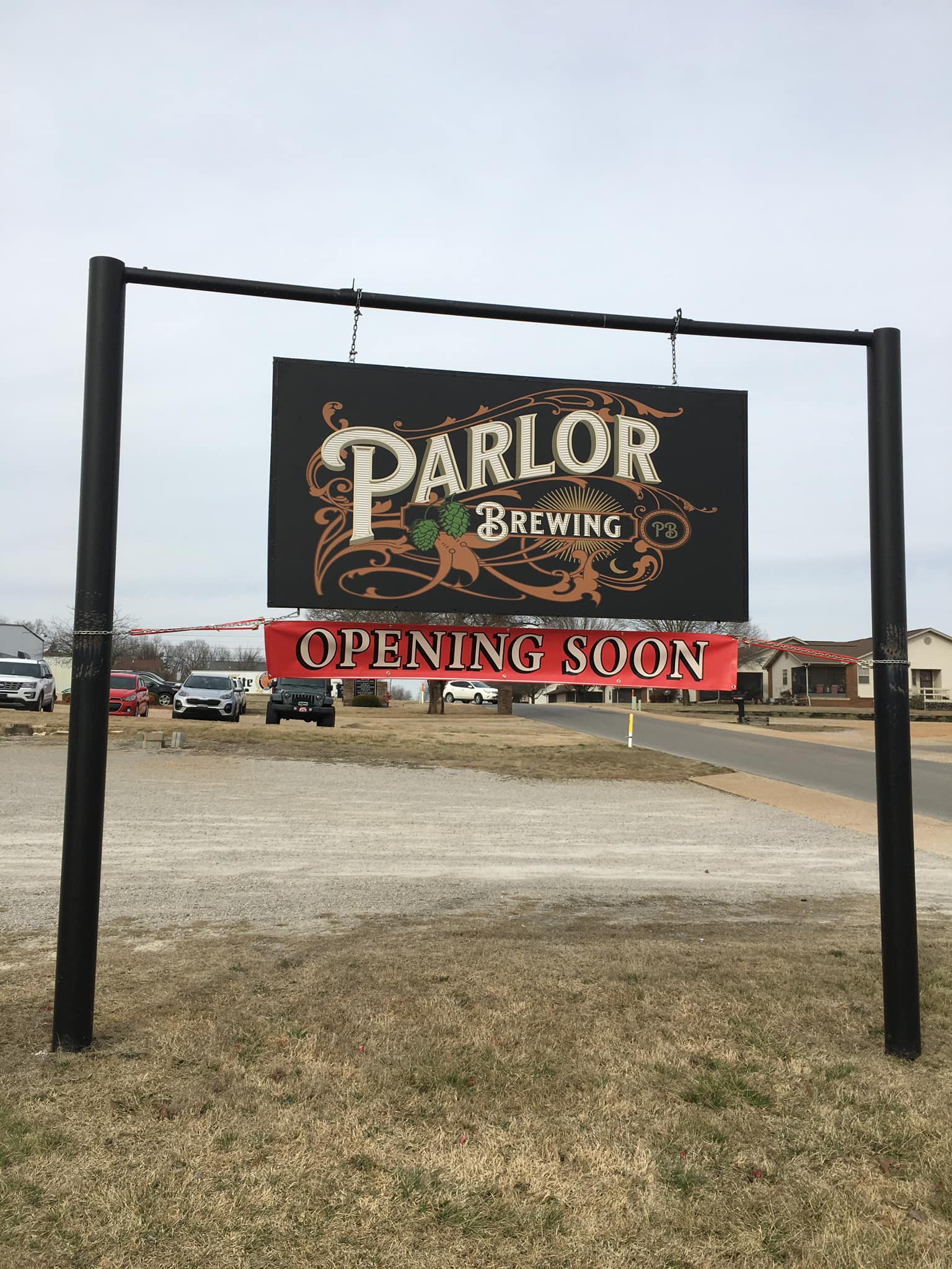 Black hanging sign for Parlor Brewing with ornate golden details and an 'Opening Soon' banner.