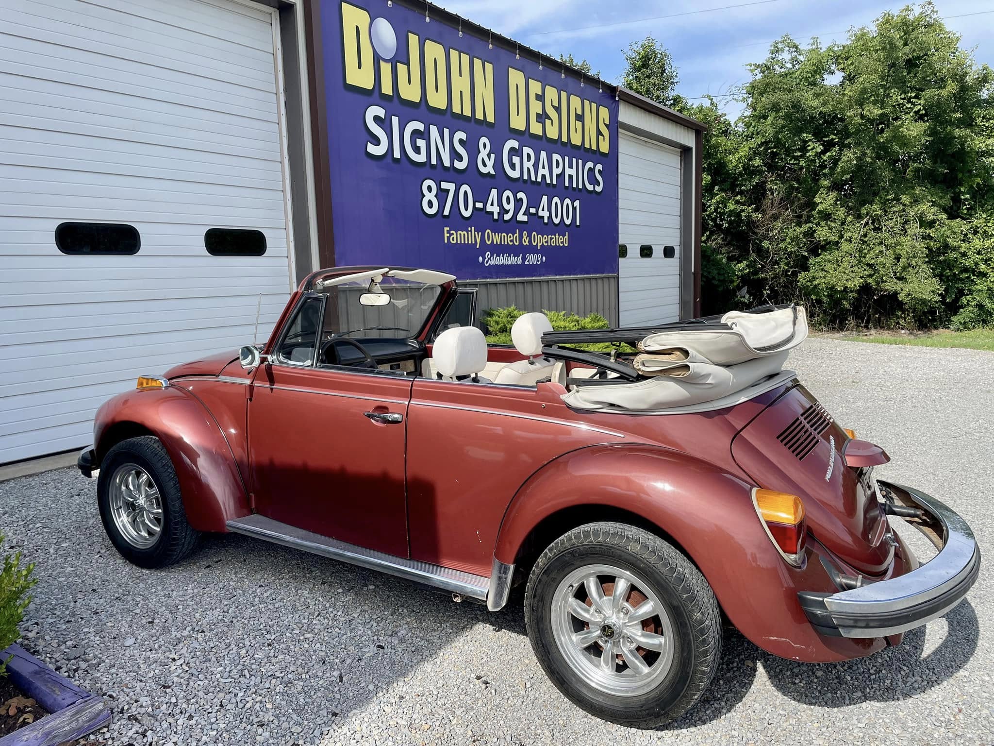 Large outdoor vinyl banner with gold and white lettering for DiJohn Designs Signs & Graphics.