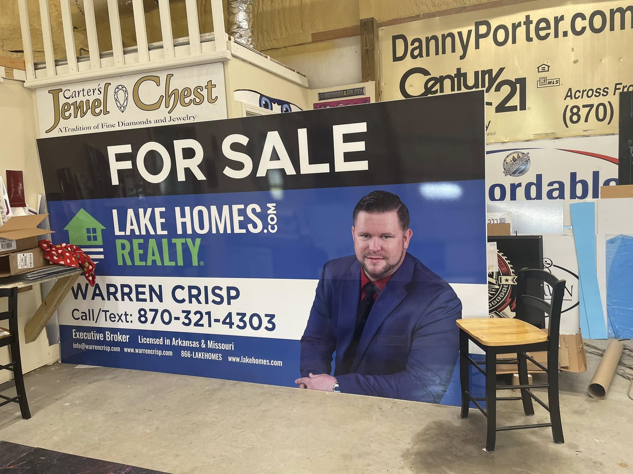 Large yard sign for Lake Homes Realty, featuring a photo of Warren Crisp, contact info, and 'For Sale' text