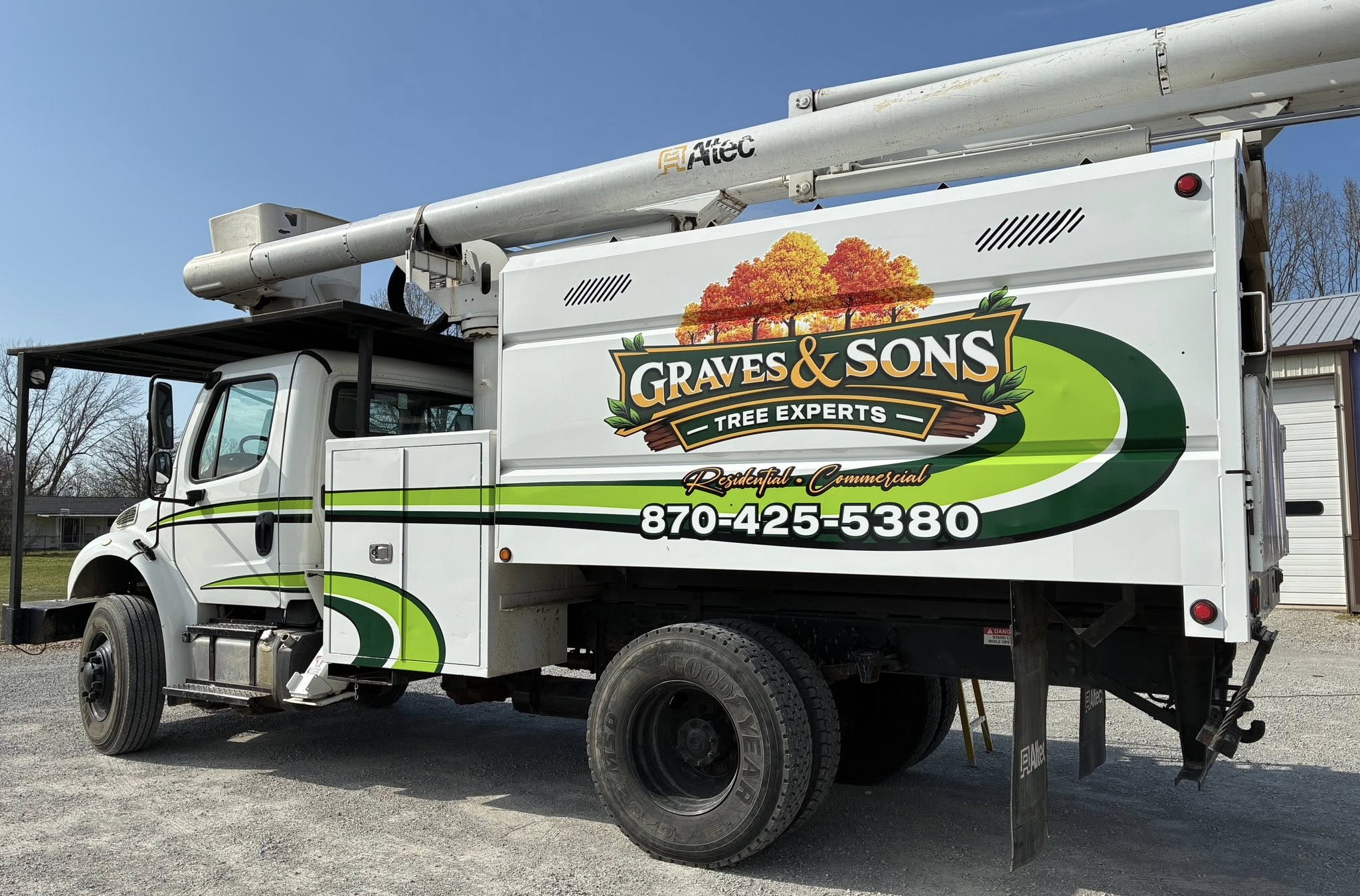 Custom full-color vinyl graphics on white tree expert service truck with green and orange accents.