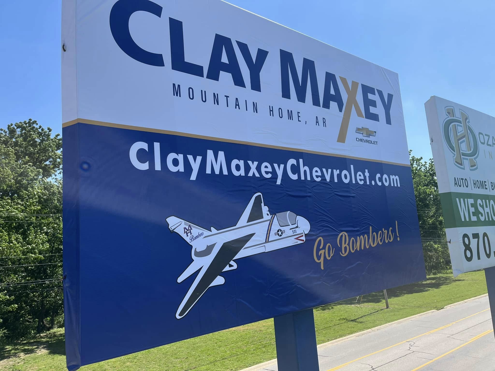 Large blue and white outdoor monument sign for Clay Maxey Chevrolet dealership advertising website.