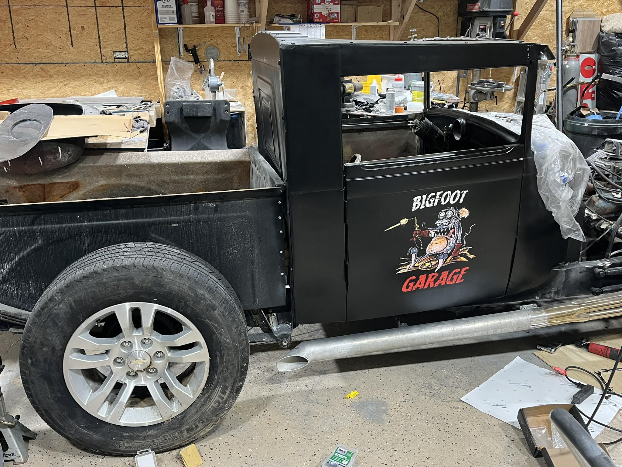 Custom vinyl graphics on black classic pick-up truck with 'Bigfoot Garage' cartoon design.