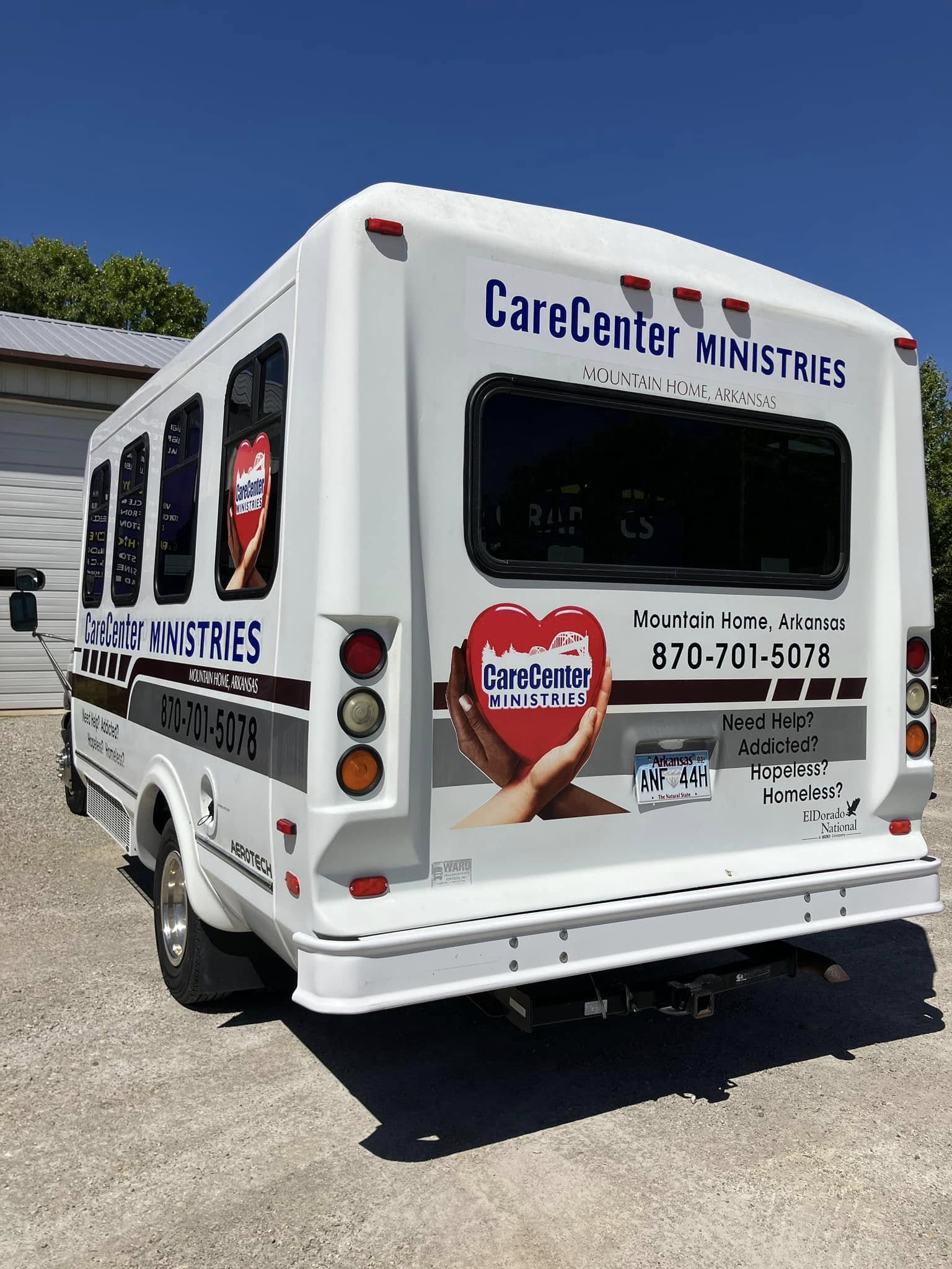 Custom graphics and text on a white shuttle bus for CareCenter Ministries in Arkansas.