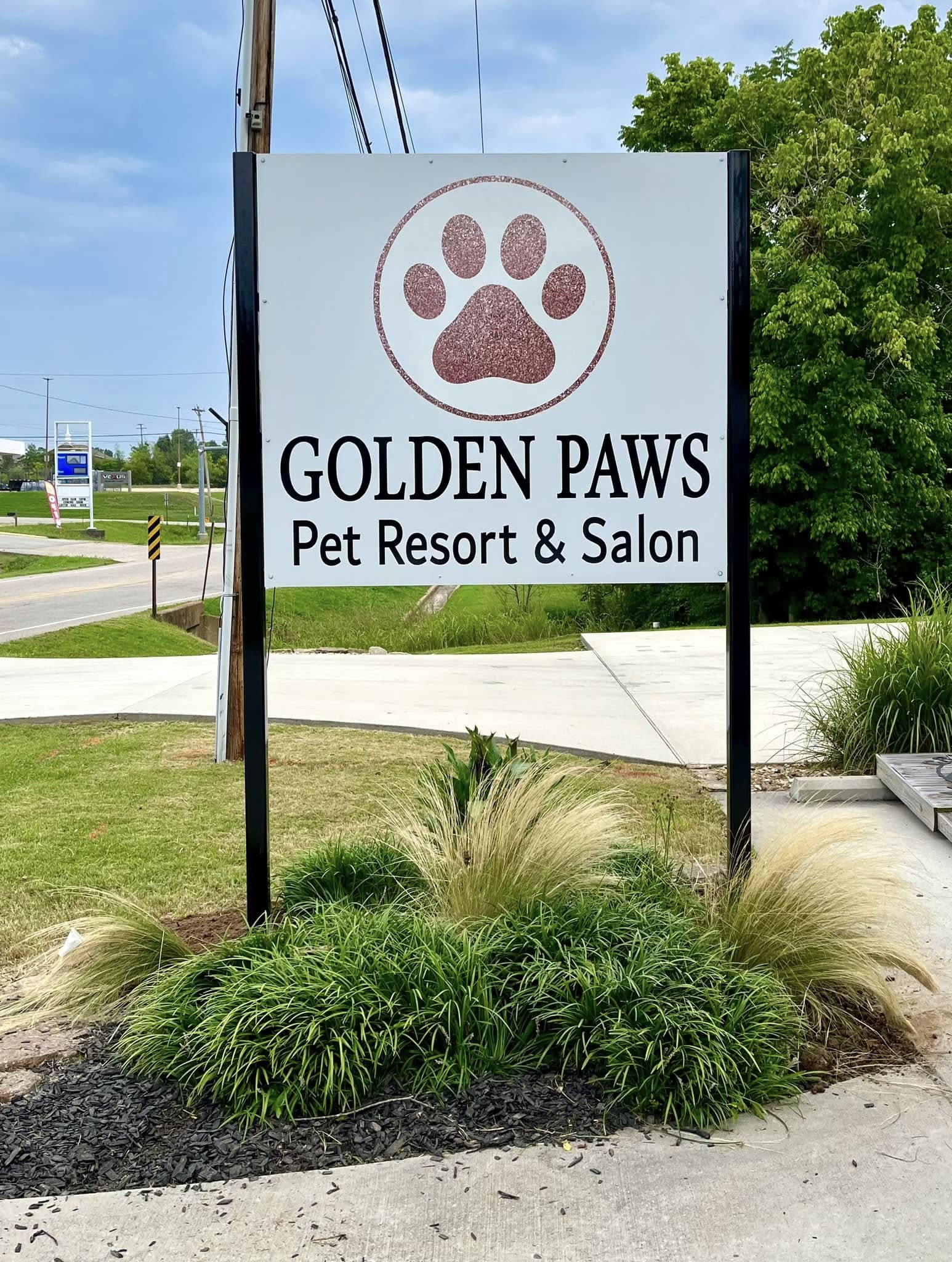 White and black monument sign for Golden Paws Pet Resort & Salon with glitter paw print logo