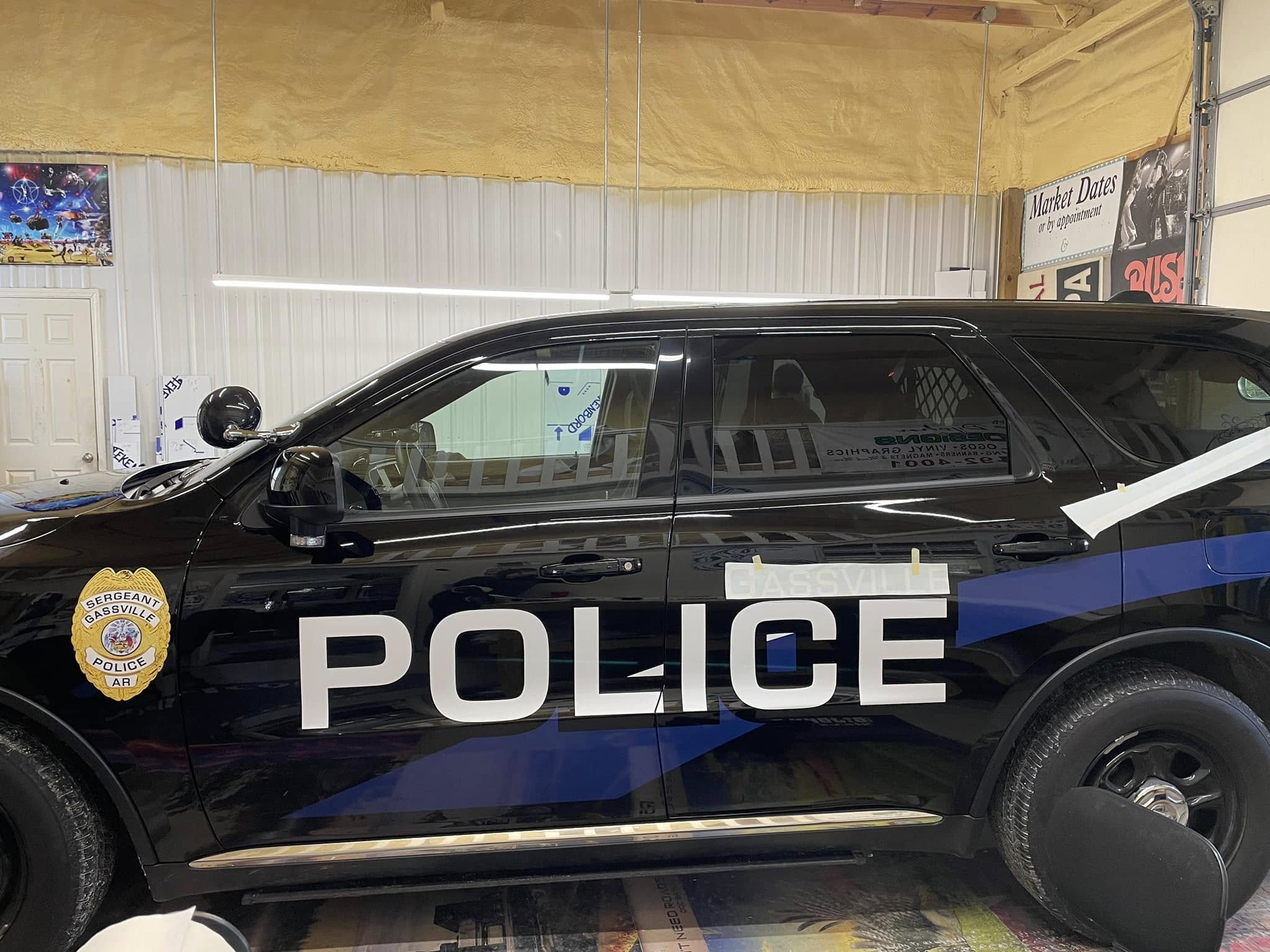 Custom vinyl graphics being applied to a black police vehicle for the Gassville Police Department.