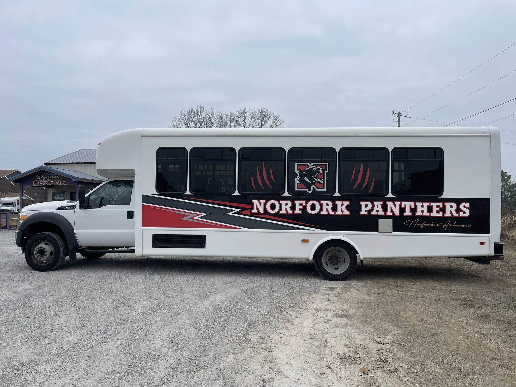 White bus with black, red, and gray partial vinyl wrap for Norfork Panthers sports team
