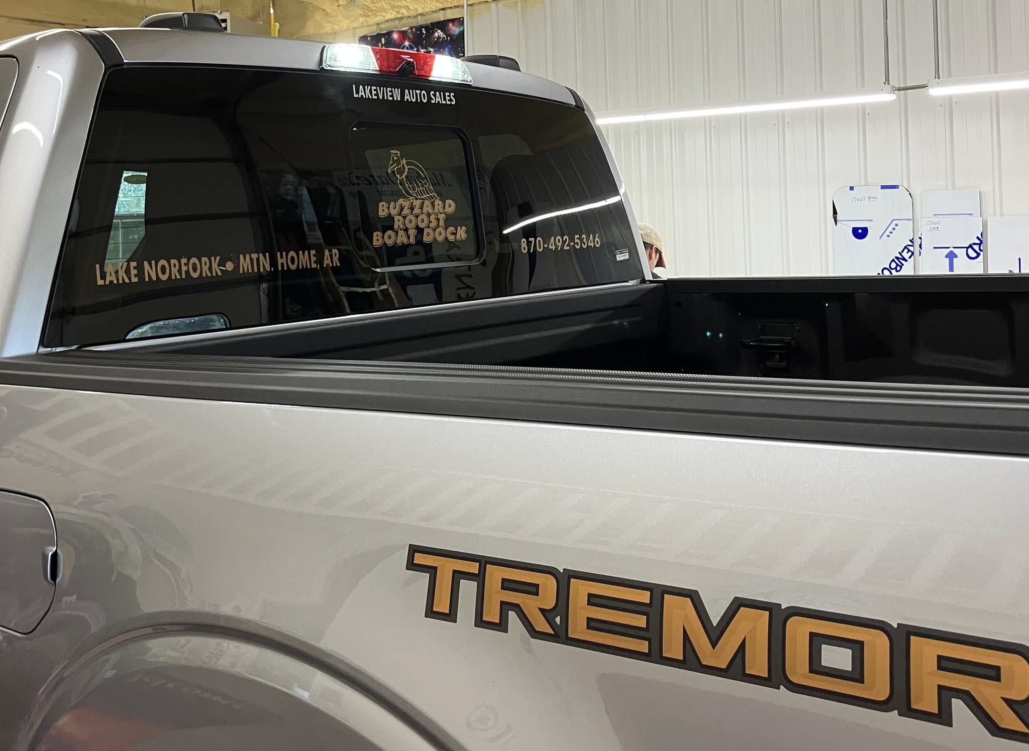 Custom gold vinyl window graphics on the back window of a light gray Ford Tremor truck for Buzzard Roost Boat Dock.