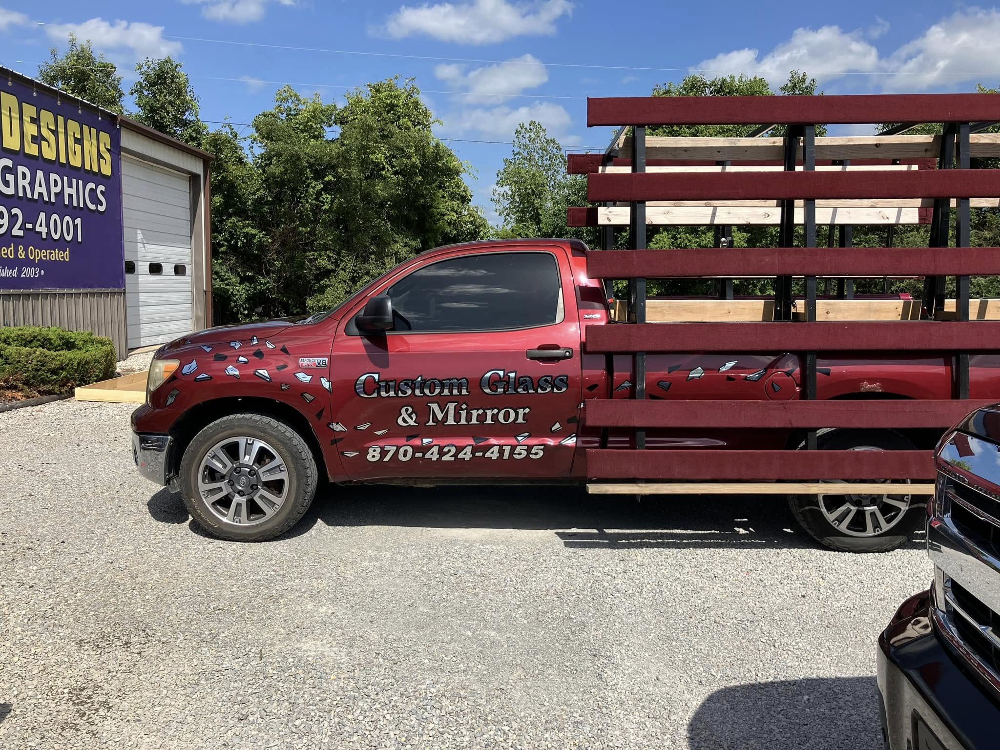 Red pickup truck with custom vehicle graphics on the side for Custom Glass & Mirror.