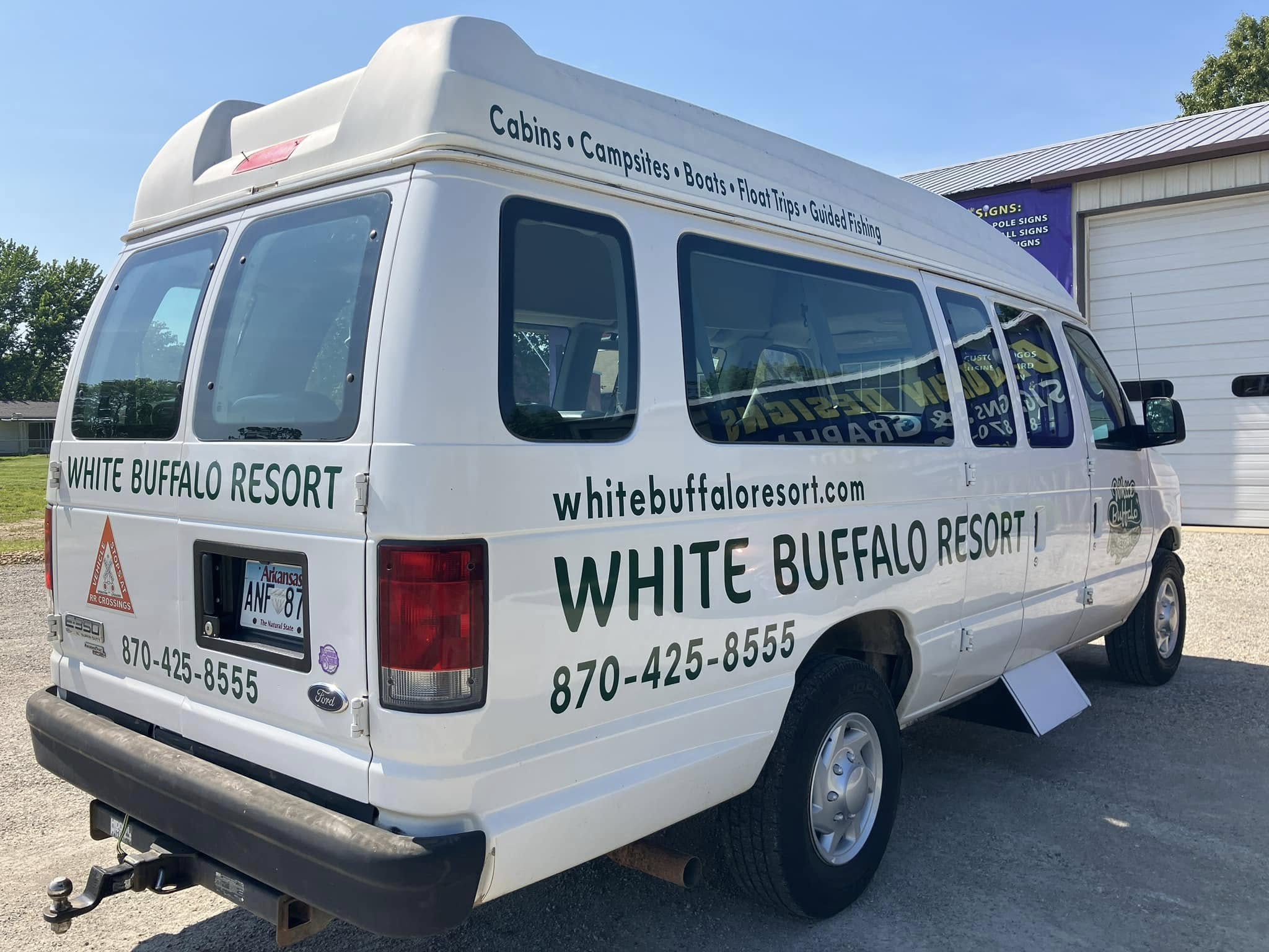 White Ford E-Series passenger van with green vinyl graphics for White Buffalo Resort