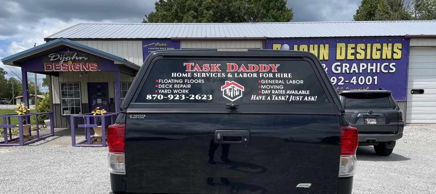 Custom vinyl graphics on the rear window of a black pickup truck for "Task Daddy" home services.