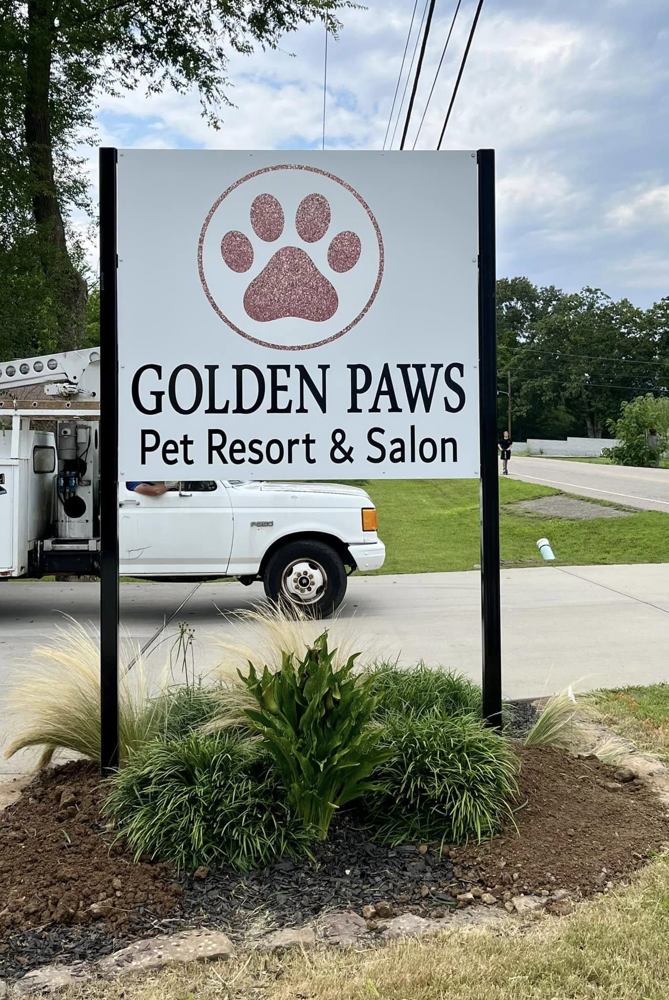 A double-sided pylon sign with glitter paw print logo for Golden Paws Pet Resort.
