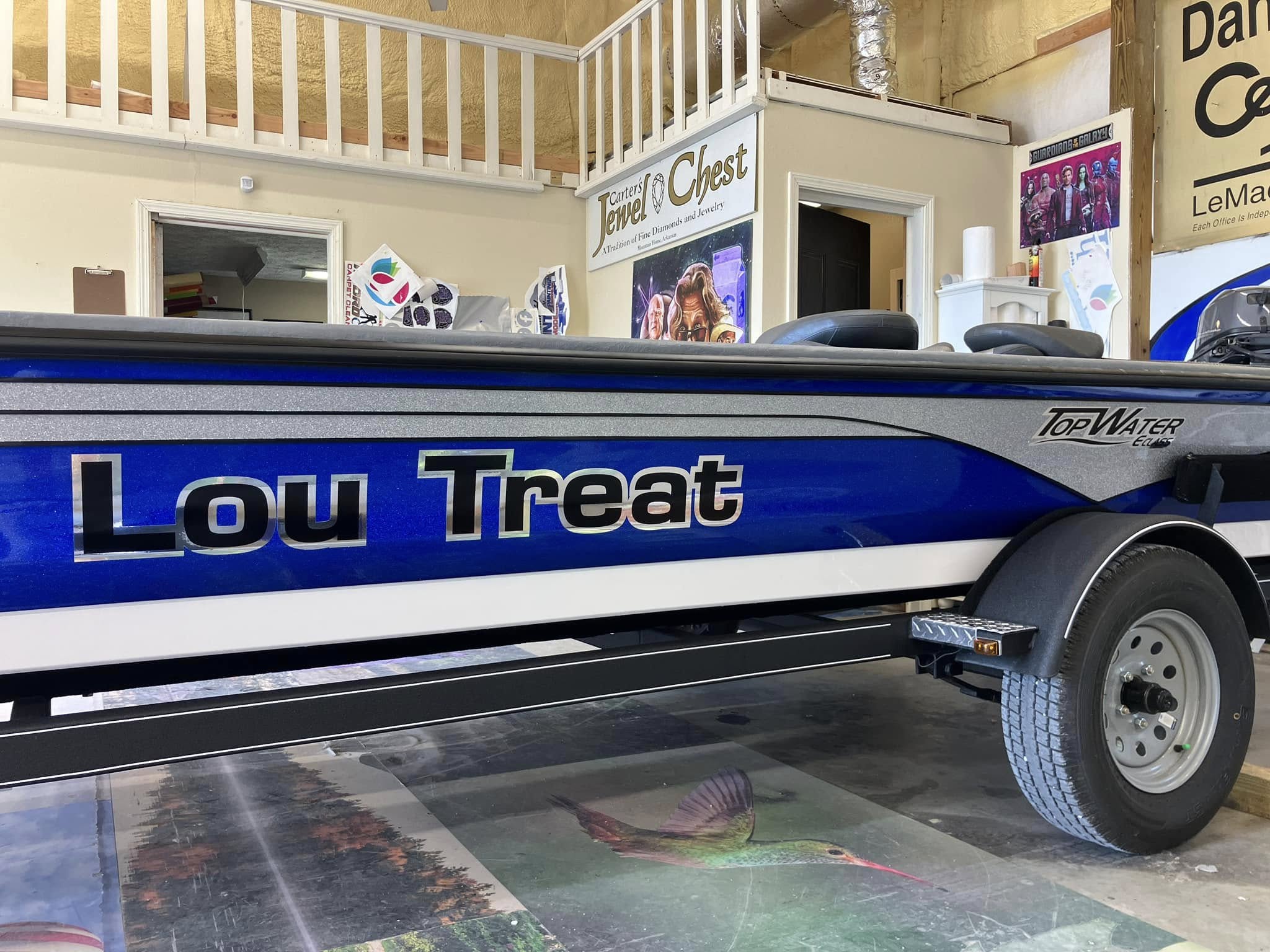 Blue and silver boat wrap with 'Lou Treat' graphics on its hull.
