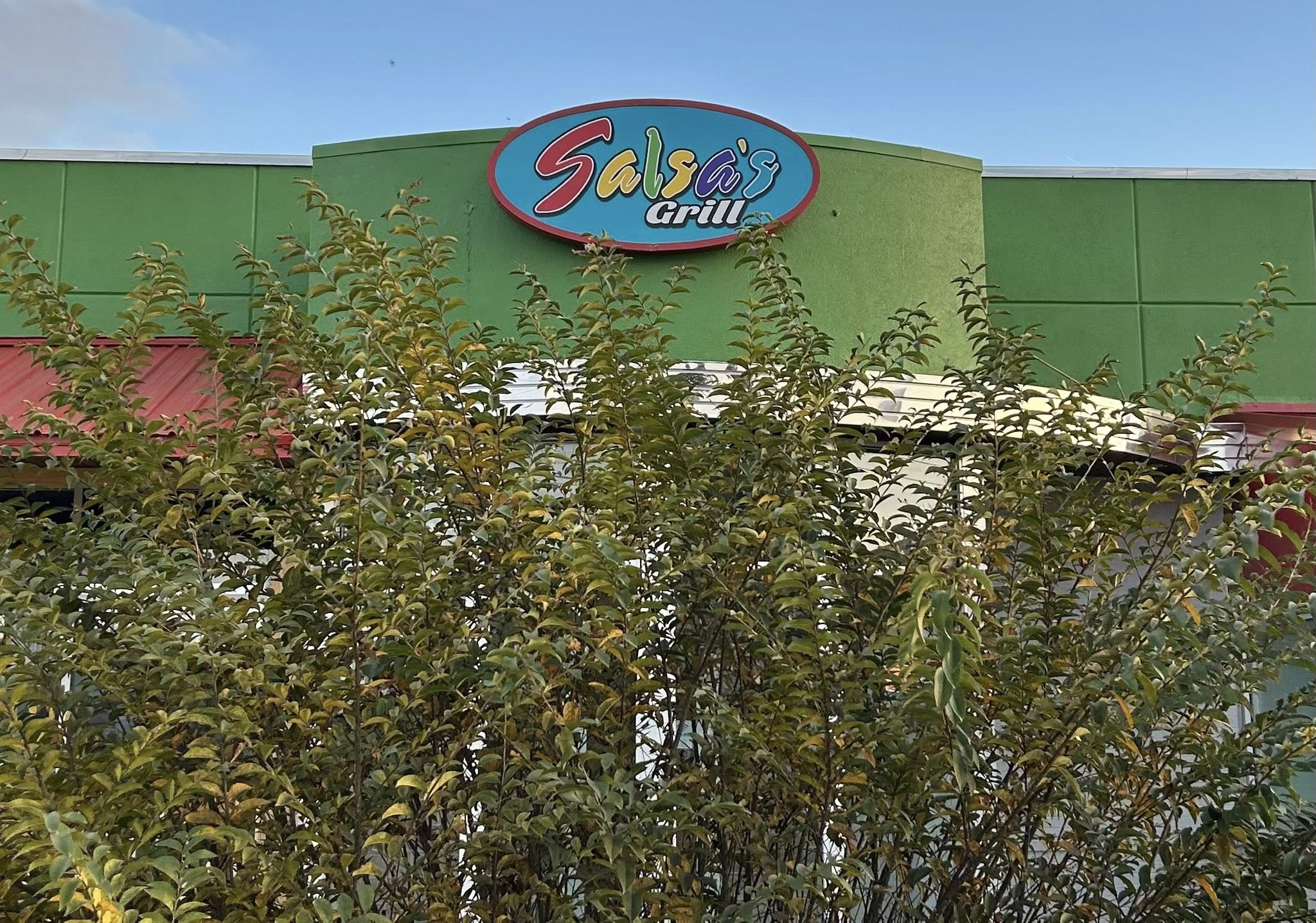 Outdoor custom sign for Salsa's Grill restaurant, red and turquoise on green facade.