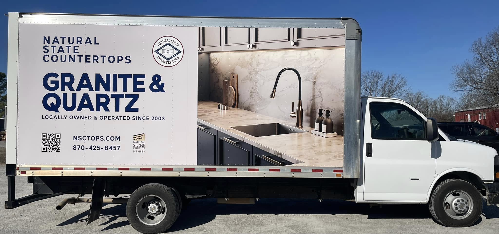 Box truck with an advertising graphic for Natural State Countertops, featuring granite and quartz.