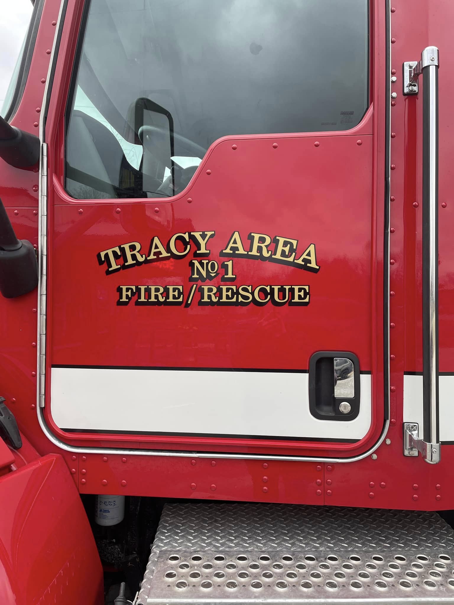 Custom gold and black lettering on a red fire truck door for Tracy Area Fire/Rescue