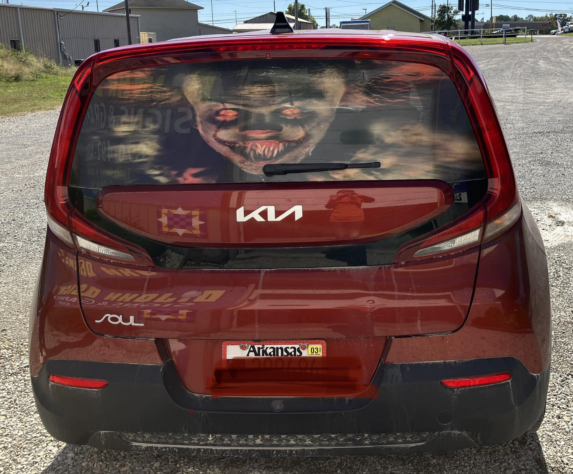 Full-color perforated vinyl graphic of a spooky clown on the back window of a red Kia Soul.