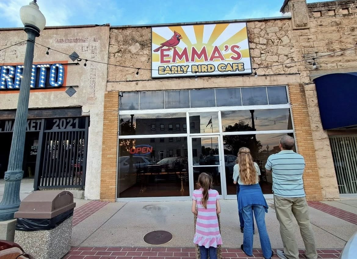 Outdoor illuminated storefront sign for Emma's Early Bird Cafe with a red cardinal graphic over the cafe entrance.