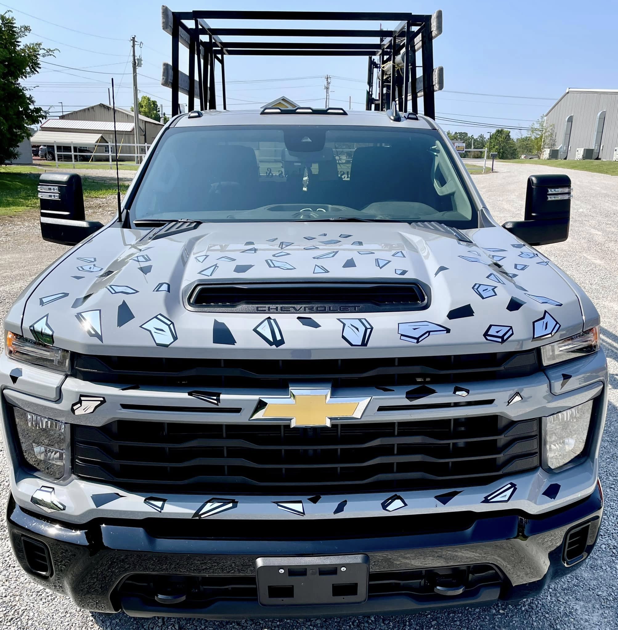 Custom graphic accents (simulating shattered glass) on light gray Chevrolet pickup truck hood and grille.