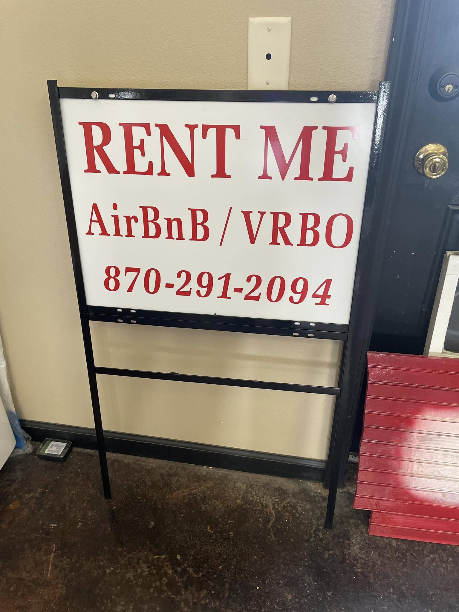 White A-frame sign with red "RENT ME AirBnB/VRBO" lettering and phone number.