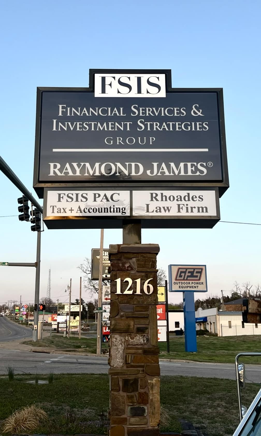A black monument sign for FSIS Financial Services & Investment Strategies Group and Raymond James.