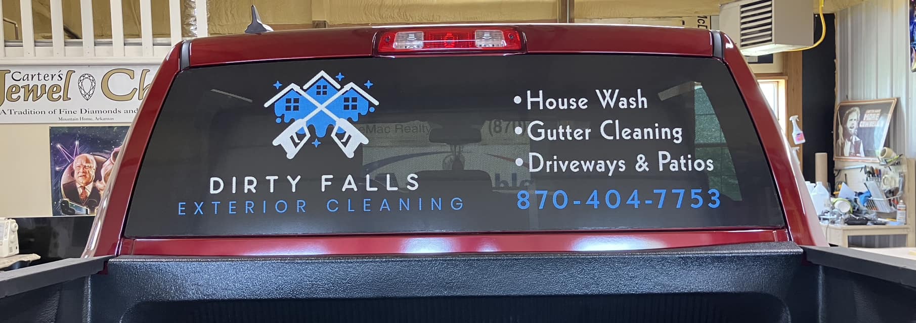 Red pickup truck with a rear window graphic for Dirty Falls Exterior Cleaning company.